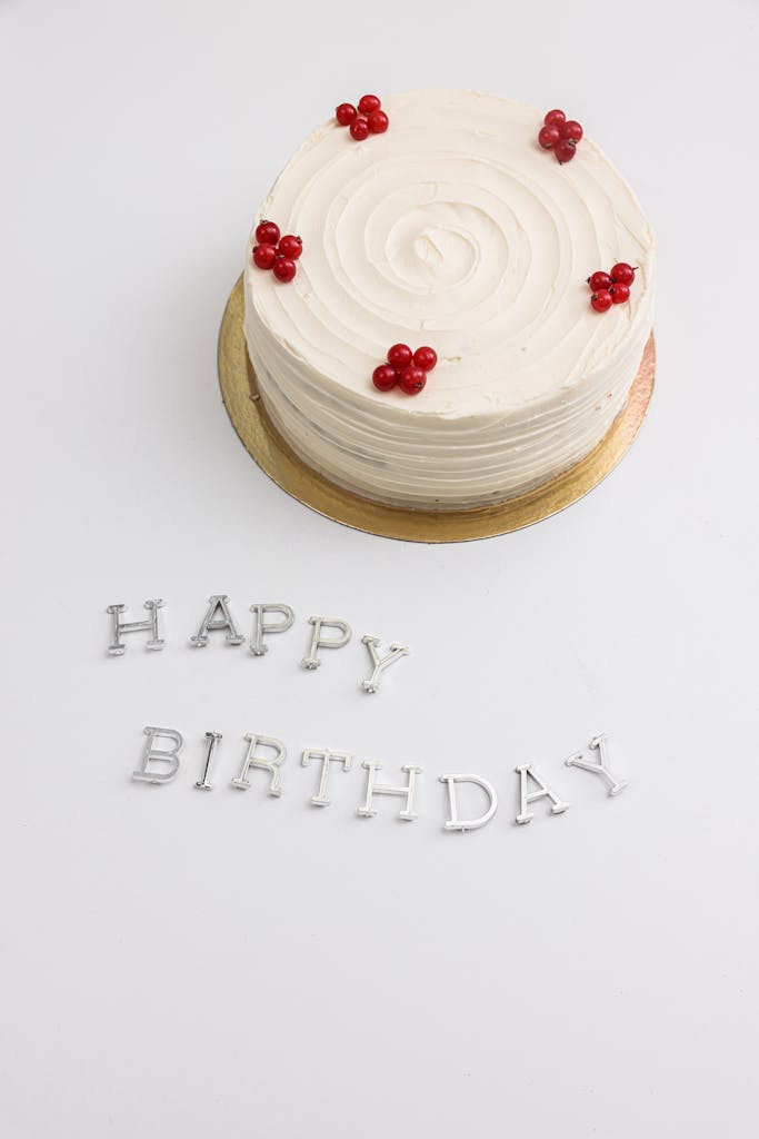 Celebratory white birthday minimalist cake decoration with berries on a minimal background with 'Happy Birthday' text.