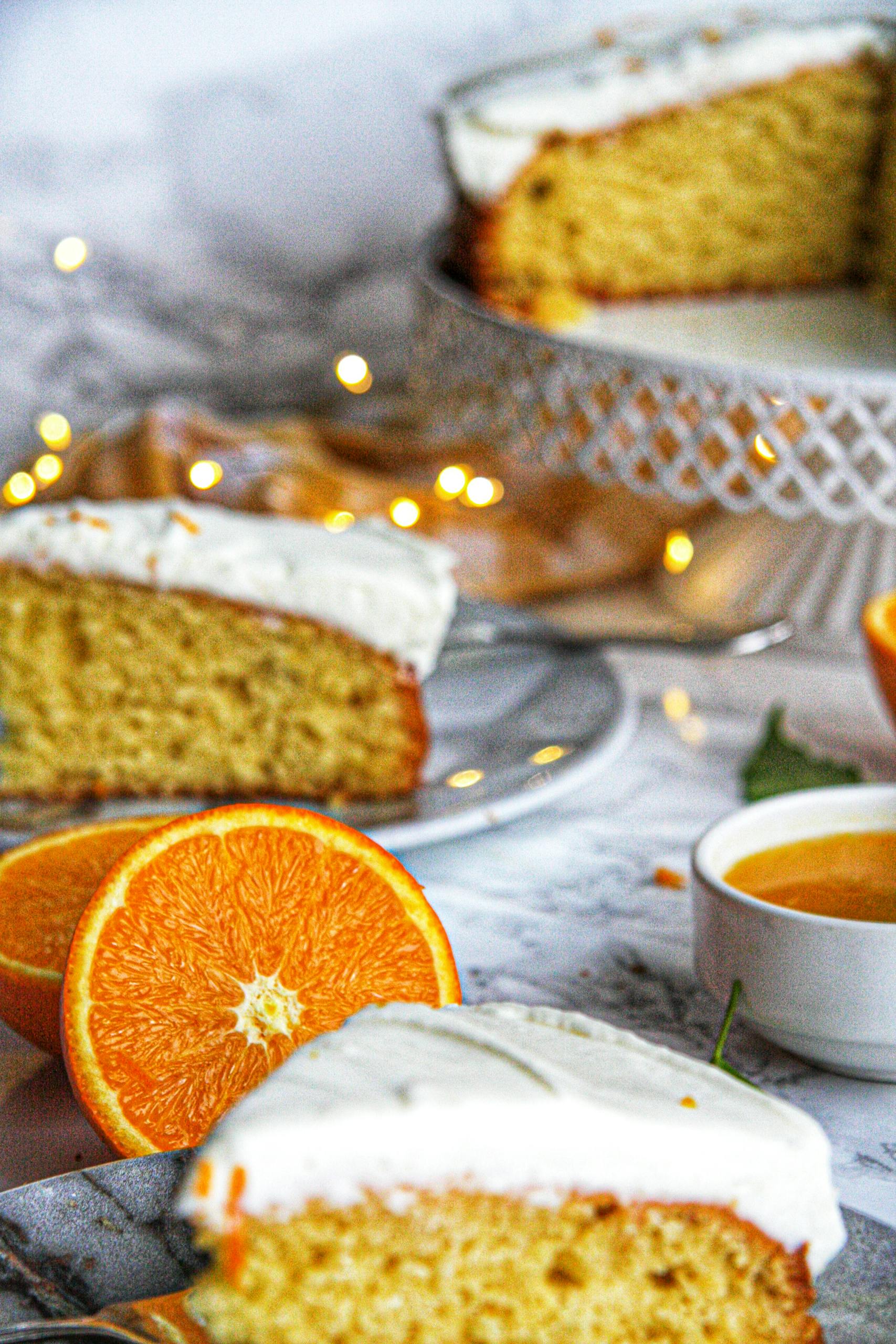 Delicious orange cake slice with frosting, garnished with fresh orange, set in a warm ambiance.