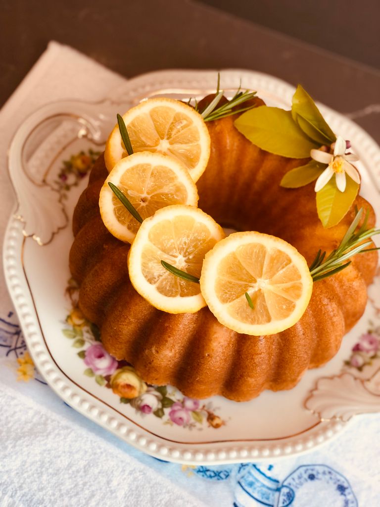 Delicious homemade lemon bundt cake garnished with lemon slices on a floral porcelain plate.