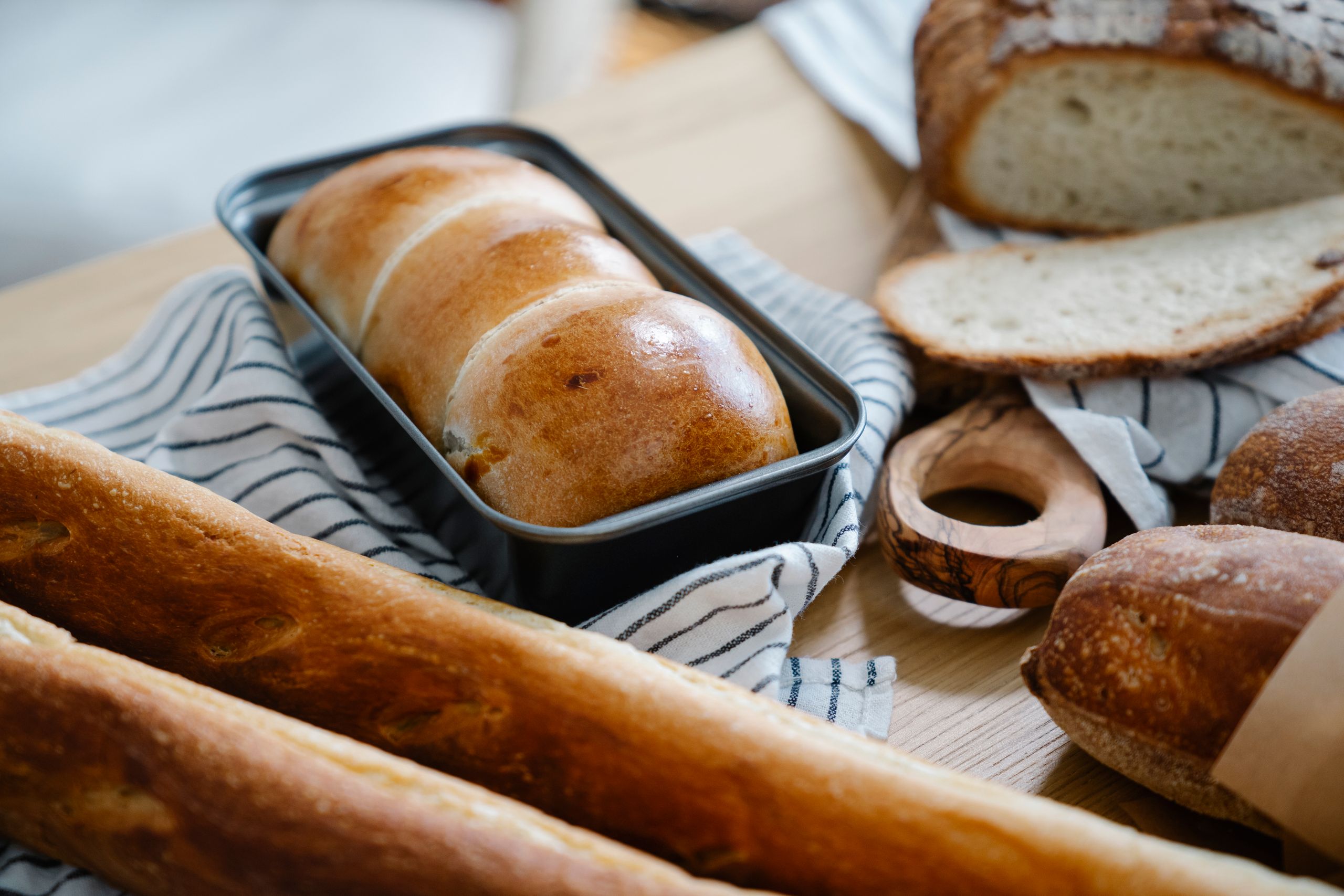 A variety of freshly baked bread displayed on a striped cloth in a cozy kitchen setting.