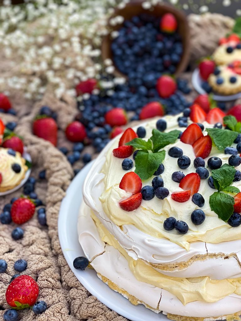 Appetizing pavlova topped with fresh berries and mint, styled on a cozy rustic background.