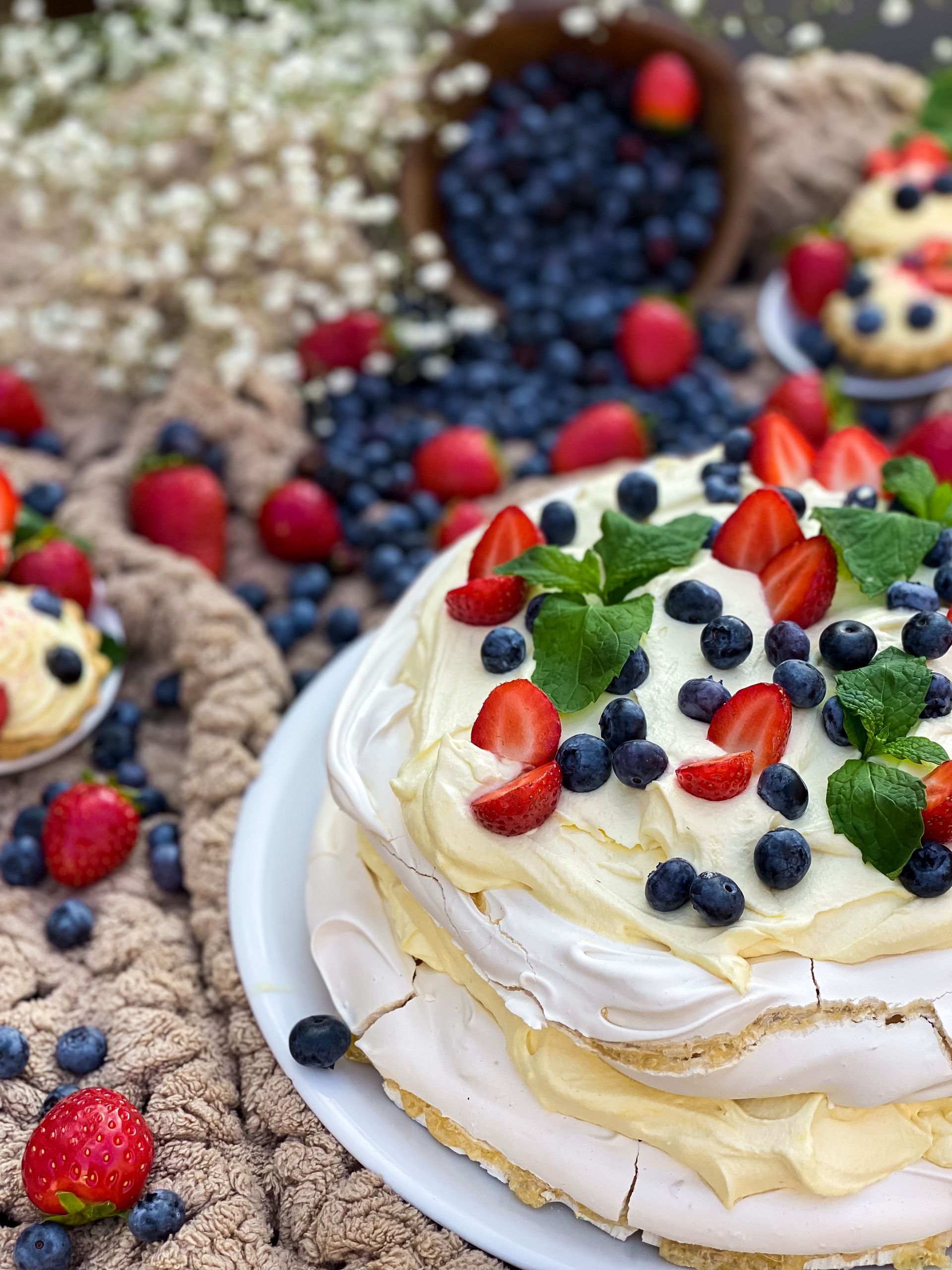 Appetizing pavlova topped with fresh berries and mint, styled on a cozy rustic background.