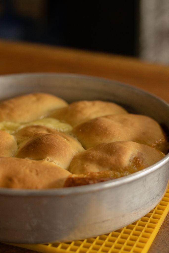 Freshly baked bread rolls in a round pan, perfect for homemade baking enthusiasts.